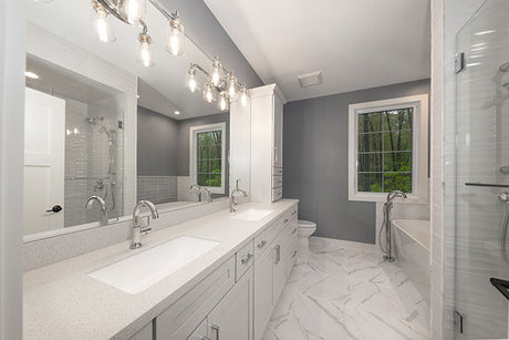 Luxury grey and white bathroom with double vanity, marble floor, freestanding bathtub, and glass shower enclosure