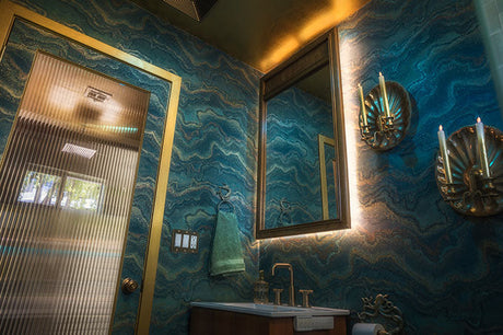 luxury powder room with blue marble wallpaper, gold mirror, wall sconces, and modern sink