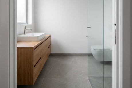 Minimalist bathroom with timber floating vanity, vessel basin, and glass partition