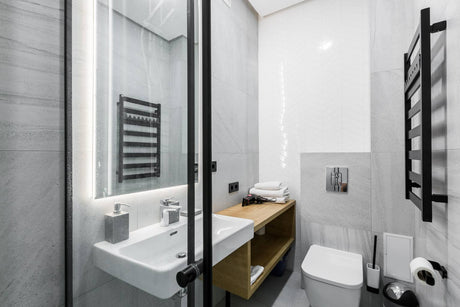 Modern minimalist bathroom with glass shower partition, wall-mounted sink, and toilet.