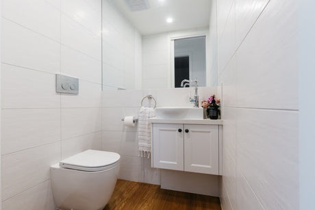 Modern powder room with wall-hung toilet, white vanity, timber floor and chrome tap