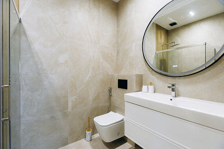 Modern small bathroom with wall-hung vanity, round mirror, and light neutral tiles