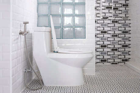modern toilet with handheld bidet sprayer, glass block window, and patterned bathroom tile