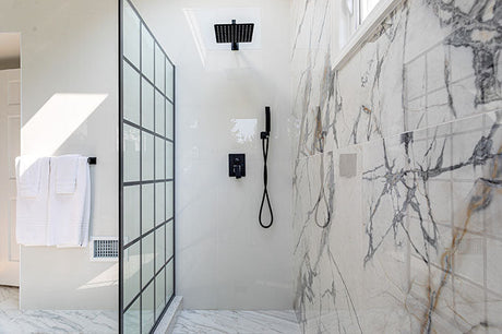  modern walk in shower with marble tile wall, glass partition, and black shower fixtures