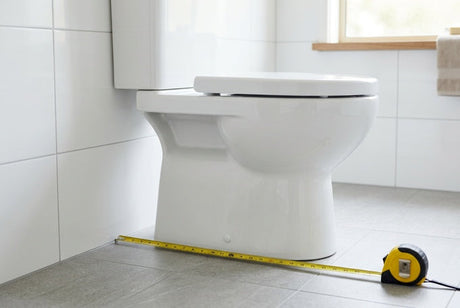 White ceramic toilet with yellow tape measure across tiled bathroom floor