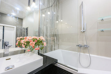 Modern bathroom featuring a white sink, bathtub with glass shower screen and stylish tiled wall finish