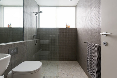 Grey mosaic tiled bathroom with frameless glass shower screen and terrazzo floor