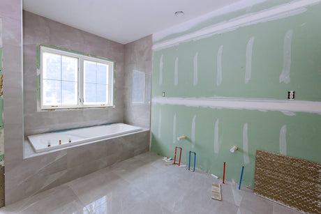 Bathroom remodel in progress with new bathtub installation and exposed plumbing lines