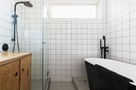 Small bathroom with black freestanding bath, glass shower, and timber vanity