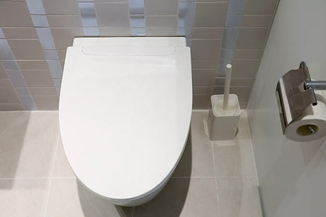 White smart bidet toilet with closed lid in a modern tiled bathroom