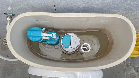 Open toilet cistern showing fill valve and flapper mechanism for repair