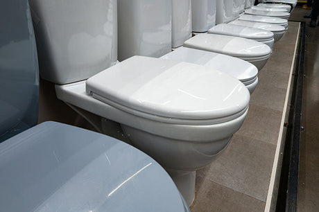 Display of bathroom toilet types in a showroom with multiple models and styles arranged in a row