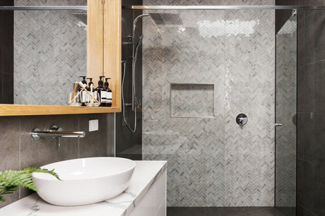 Modern bathroom with frameless glass shower screen and grey herringbone marble tiles