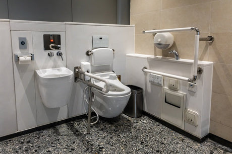 Accessible toilet cubicle with grab rails, fold-down seat, basin and bidet