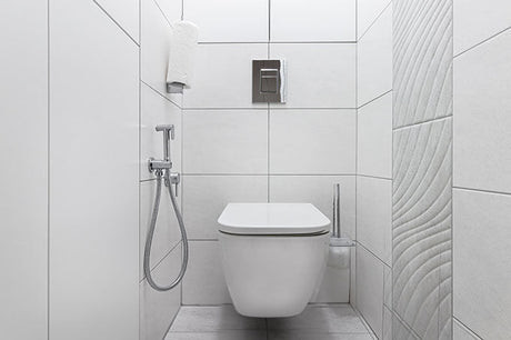 wall-mounted toilet with handheld bidet sprayer, flush plate, and white tiled walls