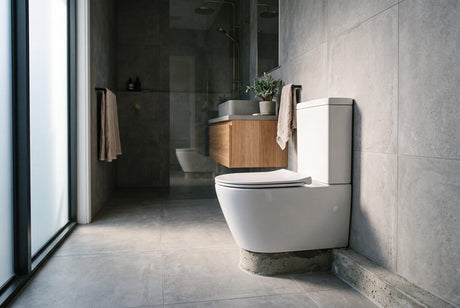 White close-coupled toilet against grey concrete tiles in modern bathroom