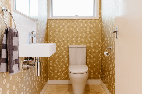 Narrow powder room with gold patterned wallpaper, wall-hung basin and toilet