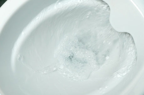 White rimless toilet with open seat and cloth draped over bowl