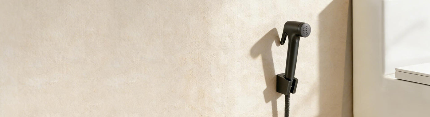 Wall-mounted black bidet spray beside modern toilet