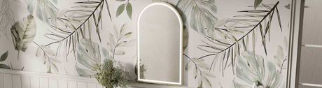 Arched framed LED mirror mounted on a tropical leaf-patterned bathroom wall
