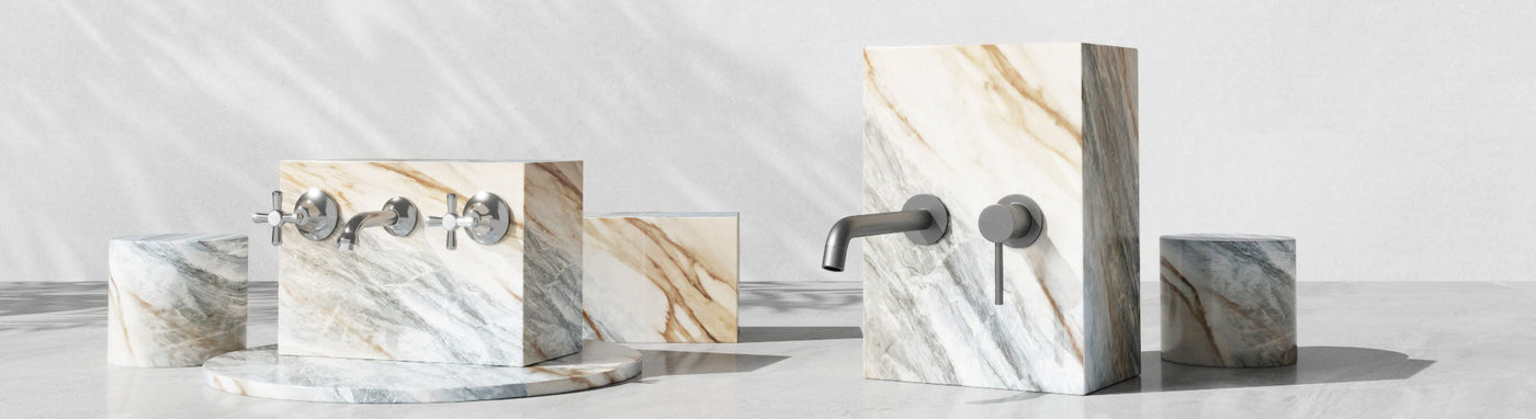 Assorted commercial laundry taps and fittings arranged on textured marble blocks.