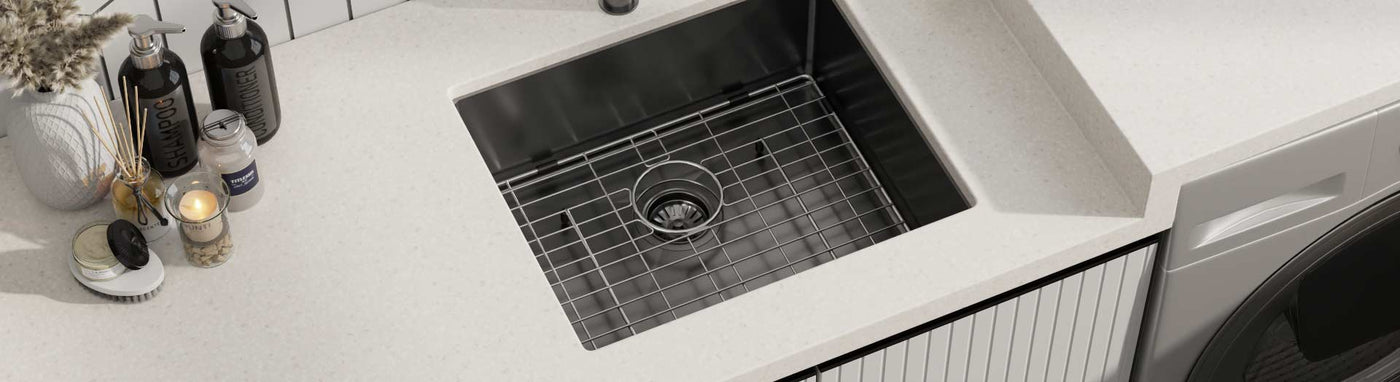 Stainless steel laundry sink with protective grid and modern accessories.