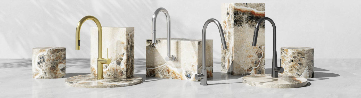 Assorted stainless steel laundry tapware displayed on marble stands with varied spout designs.