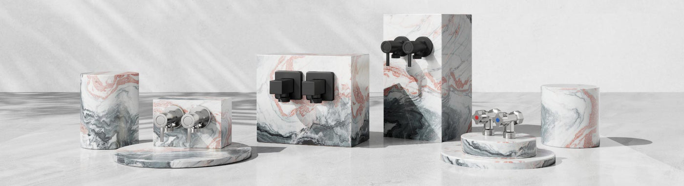 Assorted washing machine taps in chrome and matte black finishes displayed on pink and grey marble stands.