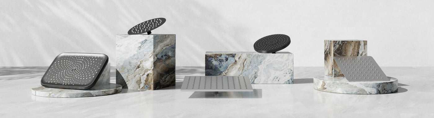 Assorted round and square shower heads in black and stainless finishes displayed on stone plinths.