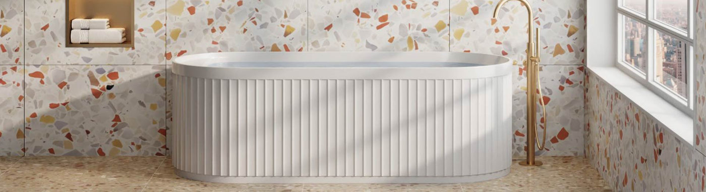 Fluted white freestanding bath with terrazzo tiles and brushed gold floor-mounted tap