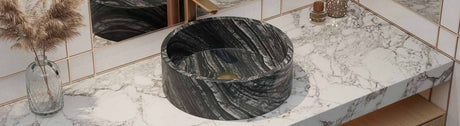 Black marble stone basin on a veined marble vanity top