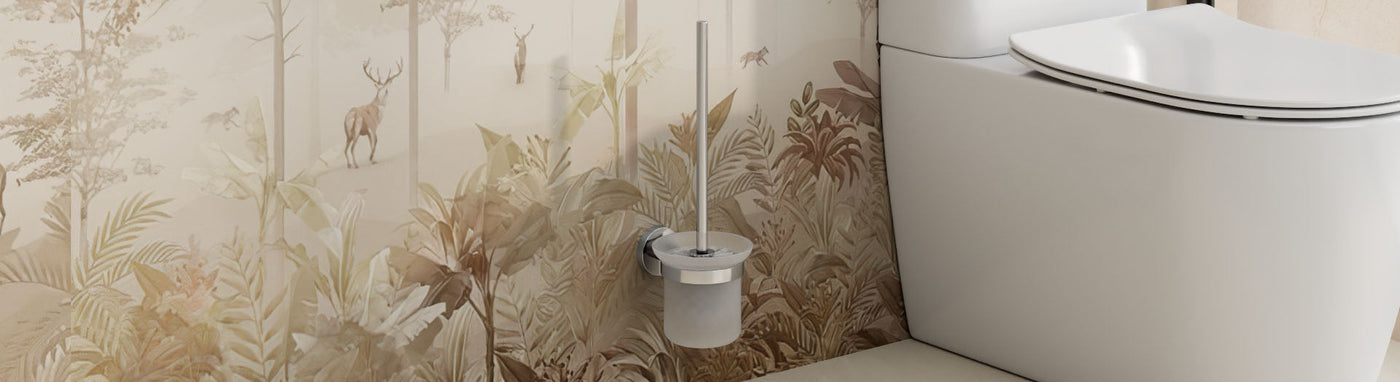 Wall-mounted stainless toilet brush with a frosted cup beside a modern white toilet against a soft botanical wall.