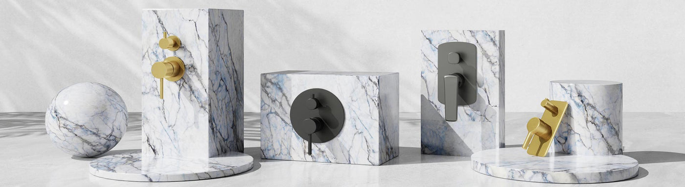 Wall mixers with diverters in brushed gold, matte black and chrome on marble plinths.