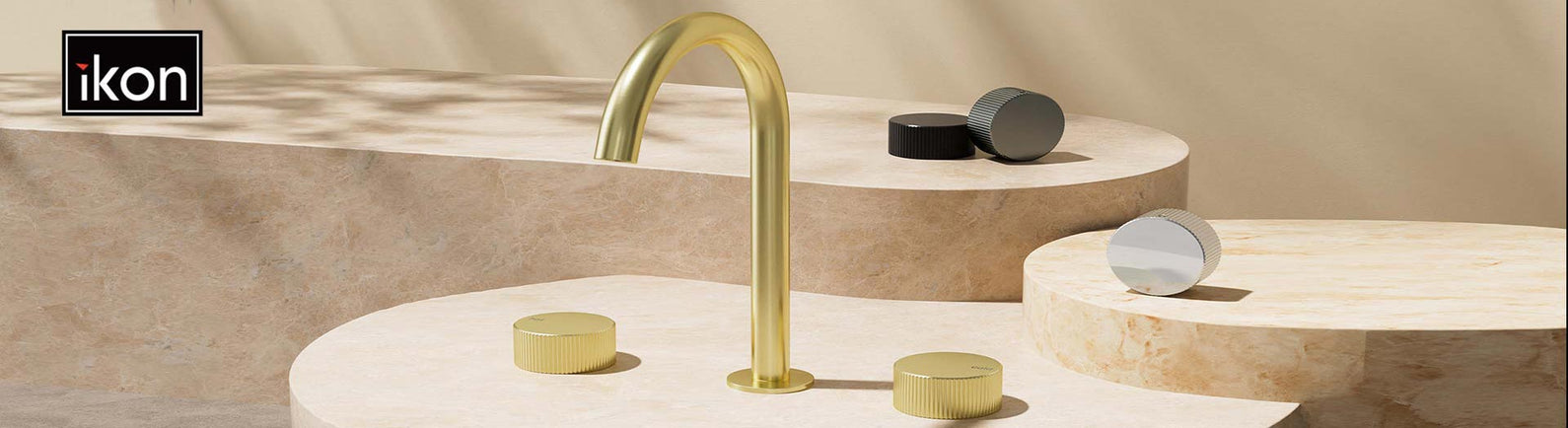 iKon brushed gold mixer on sculptural stone surfaces in a contemporary setting.