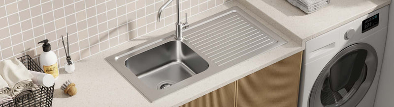 Stainless steel laundry sink with integrated drainer on a light stone benchtop